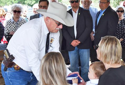 BURLESON COUNTY SHERIFF Gene Hermes presents this flag to Cindy See and the See family at the Tuesday burial at Caldwell Masonic Cemetery. See was a longtime Burleson County law officer, known for his devotion to duty and a wry sense of humor.