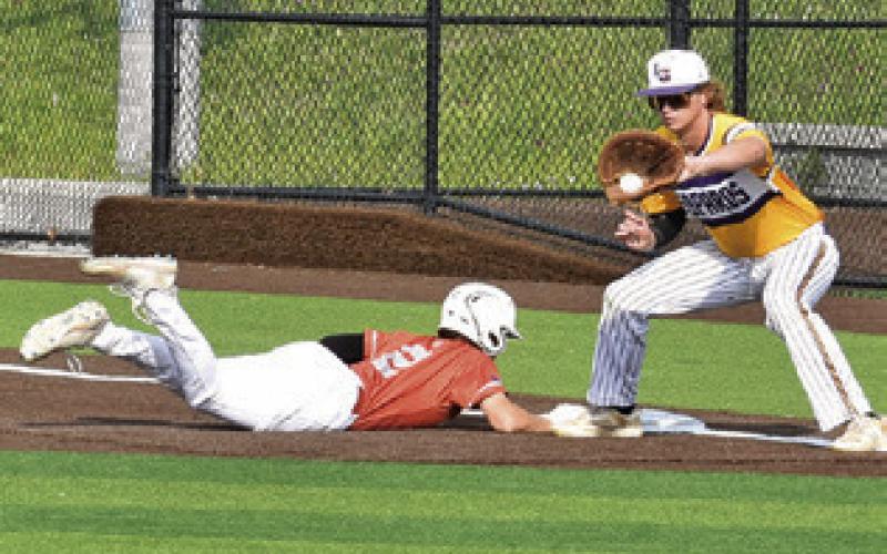 CADEN SCHLUENS SLIDES back into first base last Friday against La Grange. The Hornets won 8-3 and are headed to the playoffs. Tribune photo by Roy Sanders