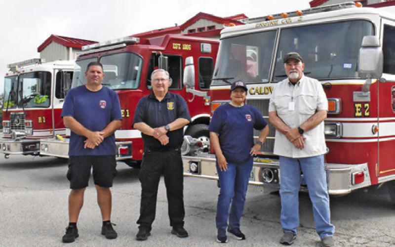 CALDWELL VOLUNTEER FIREFIGHTERS, from left, Mark Foisie, Harry Bowers, Polly Bowers and retired firefighter Doug Beavers stand next to these fire trucks at the fire station.