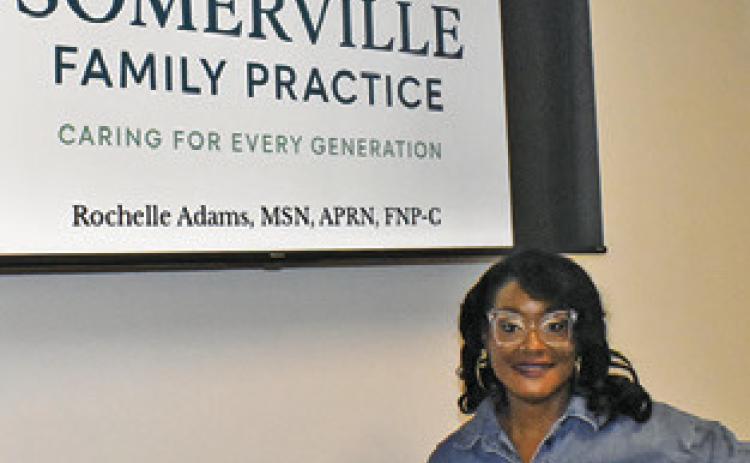 ROCHELLE ADAMS stands next to this sign at the clinic in Somerville. Tribune photo by Roy Sanders