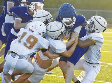 THE CALDWELL DEFENSE gang tackles this Anderson-Shiro ball carrier in the Aug. 13 scrimmage in Caldwell. Tribune photo by Roy Sanders