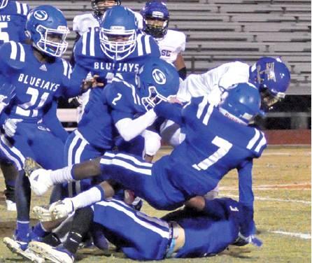 THE BLUEJAYS DEFENSE moves in on this Louise ball carrier last Friday. The Bluejays won 60-33 to secure a playoff spot. They will face Burton on Friday. -- Tribune photo by Roy Sanders