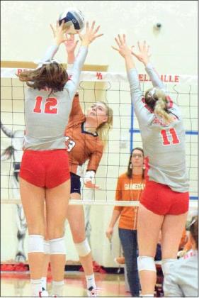 CALDWELL’S MARLEY MAURER hits the ball through the outstretched arms of Bellville’s Madison Morgan and Robbin Rice during Lady Hornets’ win over the Brahmanettes on Friday in Bellville.