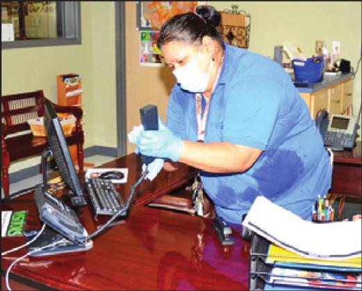 MARIA ZUNIGA cleans this desk in the office at Caldwell Elementary School.