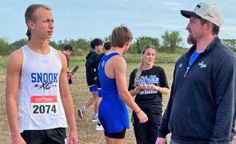 SNOOK’S BARRETT DUDENSING talks with his coach at Monday’s UIL Class 2A Regional Cross Country Championship in Corpus Christi. Dudensing placed fourth and qualified for the UIL State Meet.
