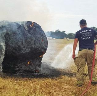 A CALDWELL FIREFIGHTER sprays water on this hay bale ignited on Thursday, Sept. 3, by a lightning strike on County Road 205. Only this bale was damaged out of a field of numerous bales at Andy Perry’s pasture, Caldwell Fire Chief Harry Bowers said.