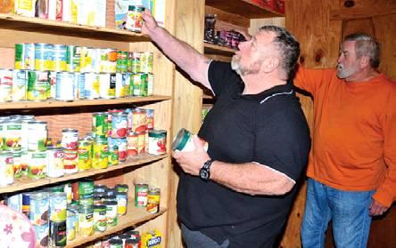 MIKE STONE AND Pat Baker look over these can goods at the Impact Burleson County food pantry. The pantry is part of Impact’s overall mission to assist the community. -- Tribune photo by Roy Sanders