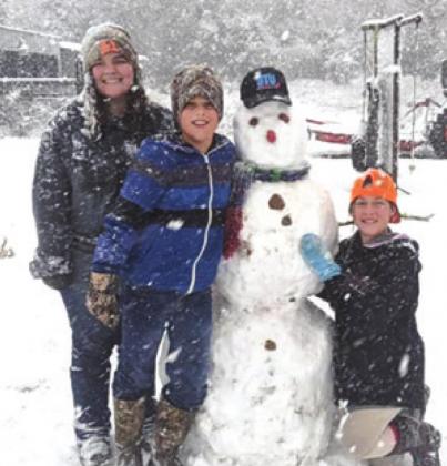 BRITNEY DAVISON and Gus and Georgi Naquin pose with their snowman in the Hix area during Sunday’s record snowfall in the county.
