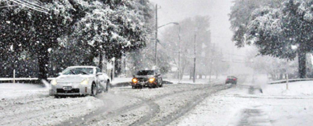 THESE CARS MOVE slowly along Buck Street on Sunday afternoon as the snow intensifies. -- Tribune photo by Roy Sanders