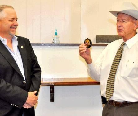 DALE STROUD DISPLAYS his badge as Burleson County Judge Keith Schroeder smiles after Stroud’s swearing in as county sheriff. Stroud replaces Thomas Norsworthy who recently resigned.