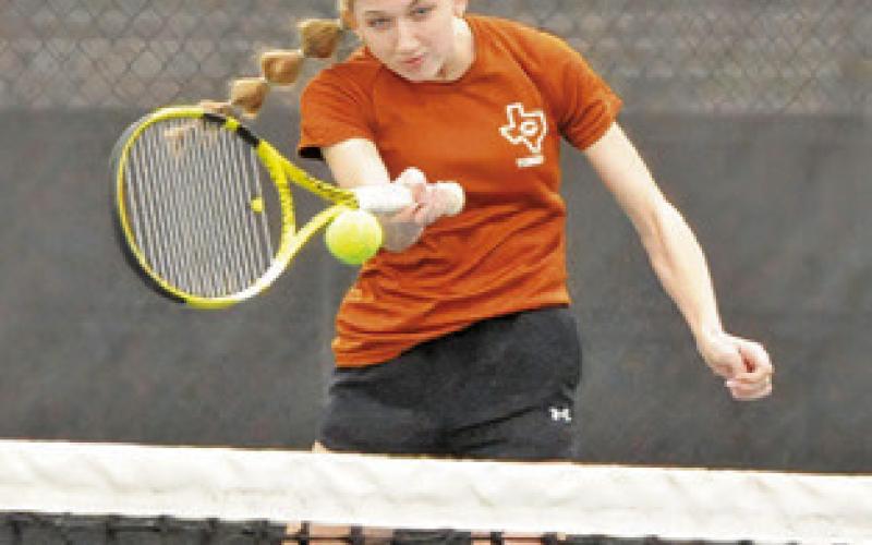TILLY HICKS RETURNS serve during a girls doubles match on Friday at the Caldwell Invitational Varsity Tournament.
