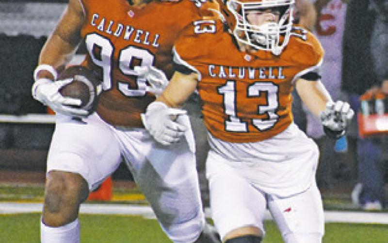 DELVIN MORRIS of Caldwell carries the ball as Thomas Willard prepares to block.