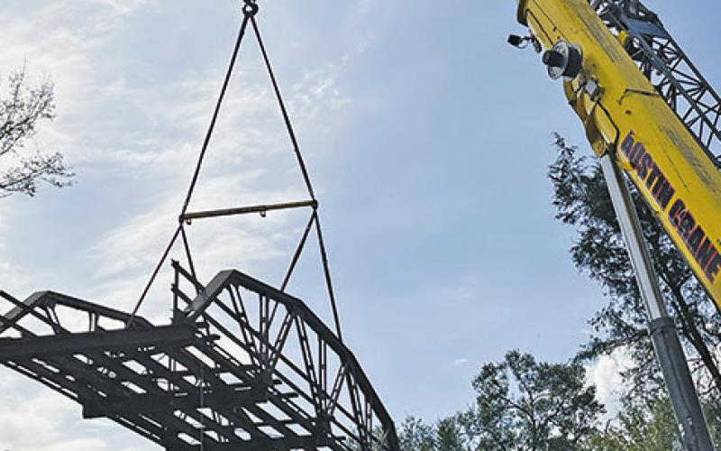 THIS OLD, historic iron bridge off County Road 146 is removed last week for a new bridge replacement. See story inside.