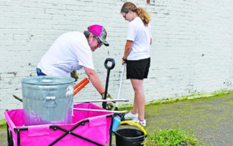 FRAN PACK AND Kylie Neuendorff work on cleanup off Eighth Street on Saturday. -- Tribune photo by Roy Sanders
