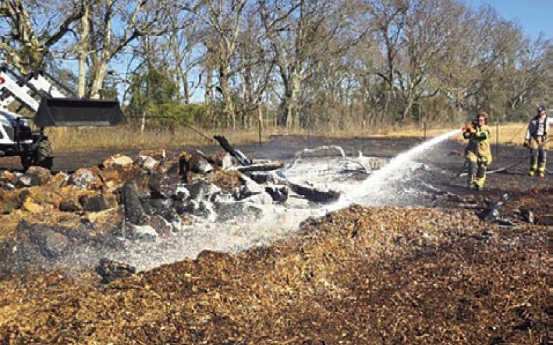 CALDWELL FIREFIGHTERS spray water on this wood pile off County Road 328. Firefighters were returning after the fire reignited. Photos courtesy of Caldwell Volunteer Fire Department.