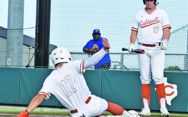 COY BECKA SLIDES into home for Caldwell against Booker T. Washington as Koy Macik observes. -- Tribune photo by Roy Sanders