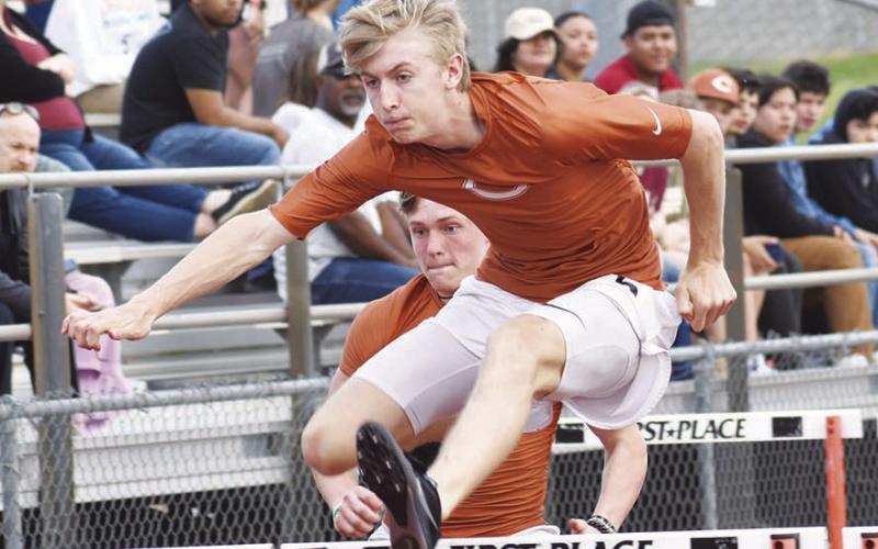 CALDWELL ATHLETE Daniel Cowan clears a hurdle during last week’s Skrabanek Relays in Caldwell. Also pictured is Corbin Stewart.