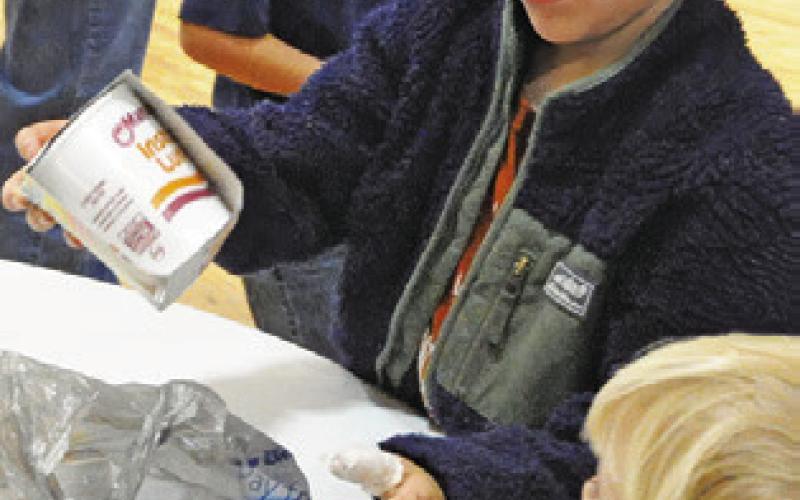 A YOUNG VOLUNTEER helps sort food at Caldwell’s annual Food for Families food drive on Wednesday, Dec. 3. Tribune photo by Denise Squier