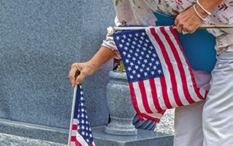 DANA YEZAK PLACES a flag at a grave marker in the Snook Cemetery on Saturday in observance of Veterans Day. Tribune photo by Denise Squier