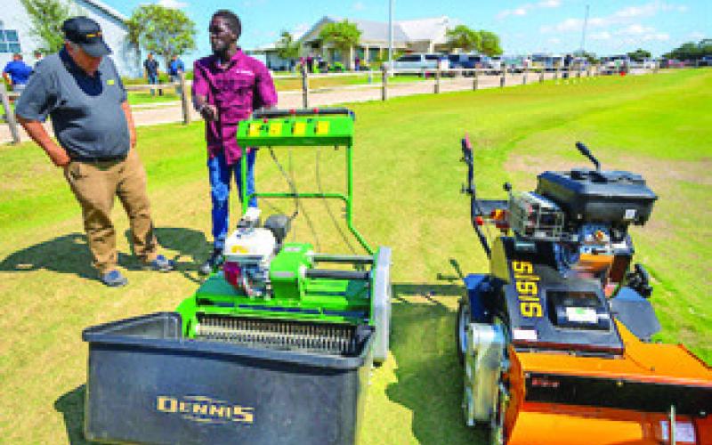 TWO MEN have a conversation next to two pieces of farm/garden equipment. Photo courtesy of Michael Miller/ Texas A&amp;amp;M AgriLife