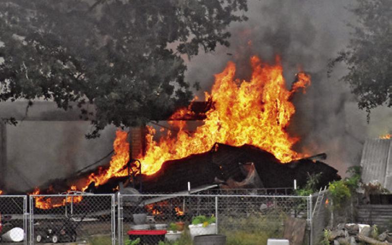 THE FIRE AT this home on F.M. 1362 South burns as area firefighters respond. The home and garage were destroyed. Tribune photo by Roy Sanders