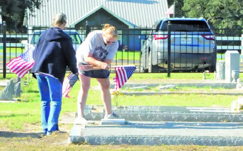 SNOOK RESIDENTS PLACE flags on veterans’ graves in the Snook Cemetery last Saturday morning. Tribune photo by Denise Squier
