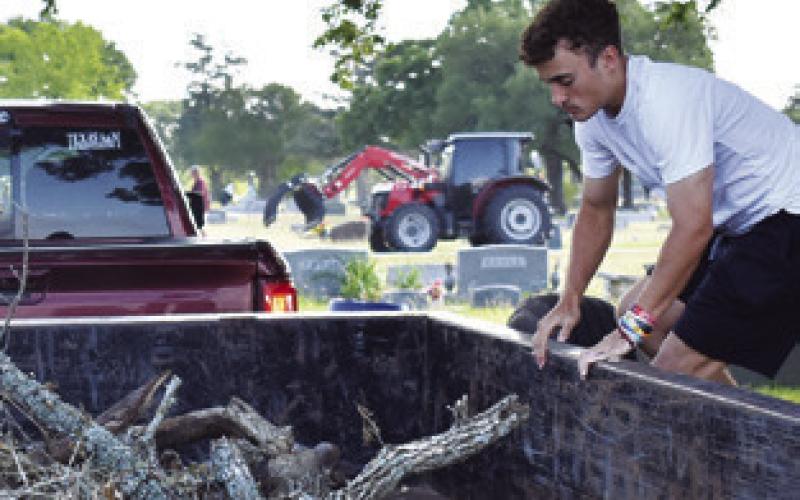 COLT HOLTON OF Somerville High School moves branches as part of the cleanup effort on Saturday at Oaklawn Cemetery.