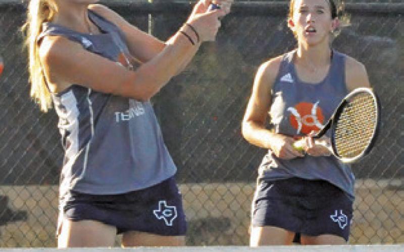 JORDAN PERKKIO hits a volley while her teammate Kylie Vogler looks on during the Caldwell-Taylor team tennis match Monday. Tribune photo by Denise Squier
