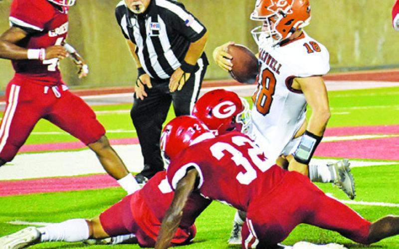 CALDWELL’S CARSON PARKER is tackled by Groesbeck defenders. The Hornets lost the opener 41-0. -- Tribune photo by Roy Sanders