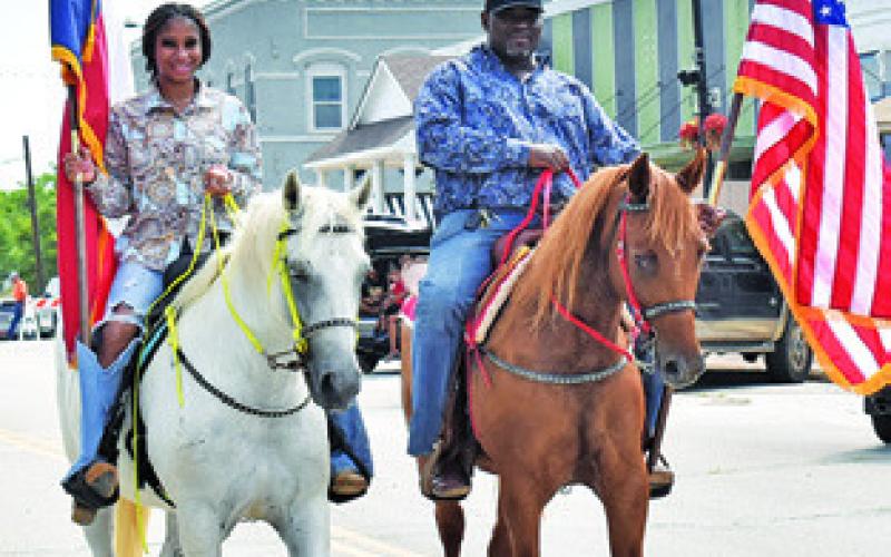ROGER AND RACHEL Richmond carry the U.S. and Texas flags on horseback to start the annual Juneteenth Parade in Caldwell.
