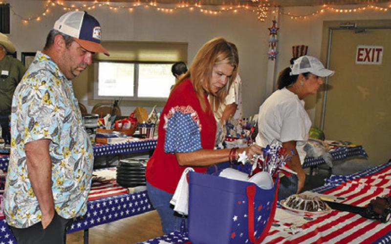 THOSE ATTENDING THE Deanville July 4 celebration look over these auction items at the Sons of Hermann Hall off F.M. 111.