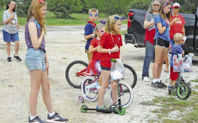 THOSE ATTENDING THE July 4 Fun Walk/Run event paused to honor America with the playing of the National Anthem. Tribune photo by Denise Squier