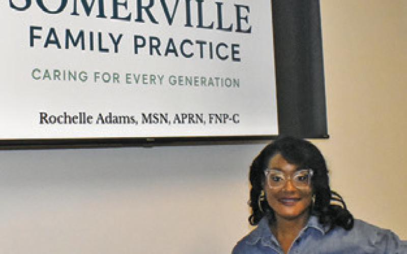ROCHELLE ADAMS stands next to this sign at the clinic in Somerville. Tribune photo by Roy Sanders