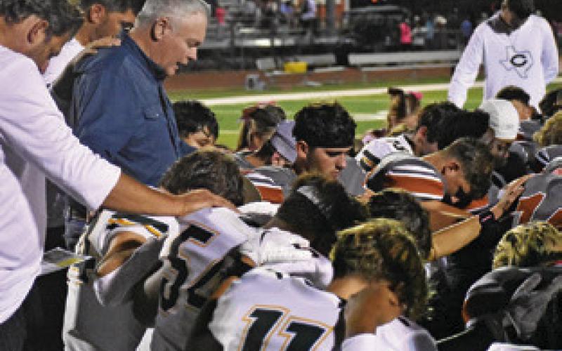 CALDWELL AND LEXINGTON players pray together on Friday for Jurian Moore who was injured in the game. Tribune photo by Roy Sanders