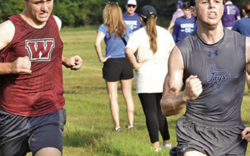 SNOOK’S ETHAN JANAC, RIGHT, crosses the finish line of Saturday’s Caldwell Cross Country Invitational Meet, edging out Heber Brown of Waller for fourth place. Tribune photo by Roy Sanders