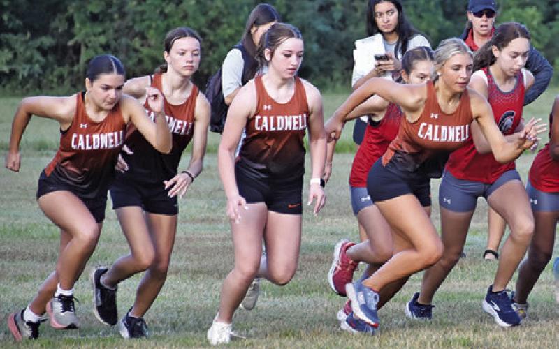 THE CALDWELL VARSITY girls cross country runners leave the starting line of the Caldwell Cross Country Invitational Meet on Saturday at Hejl Park at Davidson Creek in Caldwell. Tribune photo by Roy Sanders