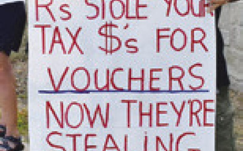 PROTESTERS CARRY signs on Saturday to protest the Republican redistricting plan.