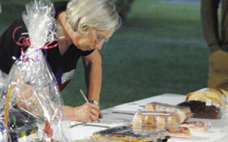MARGARET POLANSKY PLACES a bid in the silent auction at the Cops4Kids fundraiser at Snook City Park on Saturday. Cops4Kids collects school supplies during its Stuff the Bus drive and provides senior scholarships at all three area schools. Tribune photo by Denise Squier