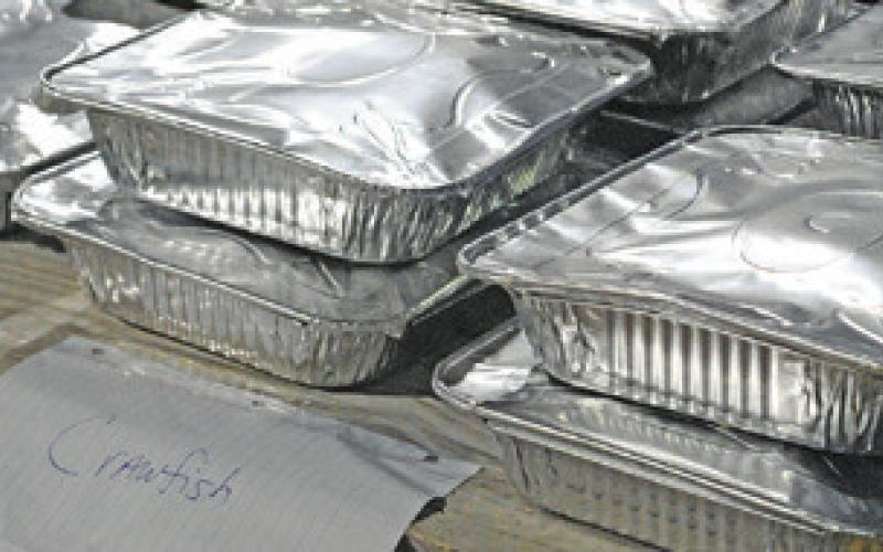 ALUMINUM TINS FILLED with crawfish, potatoes, sausage and corn were for sale for $25 each at Saturday’s shrimp and crawfish dinner fundraiser for Cops4Kids at the Snook City Park. Tribune photo by Denise Squier