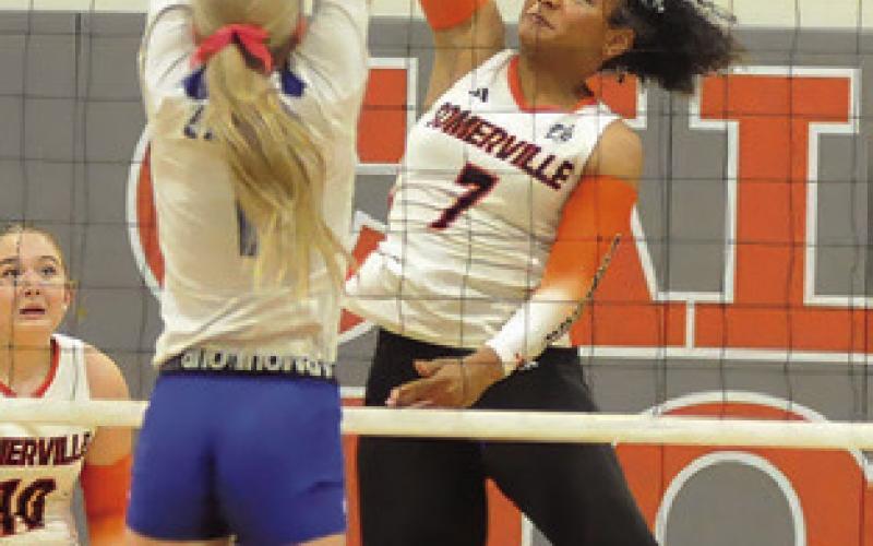 EMMA WILLIAMS hits the ball while Kennedi Withem attempts to block. Tribune photo by Denise Squier