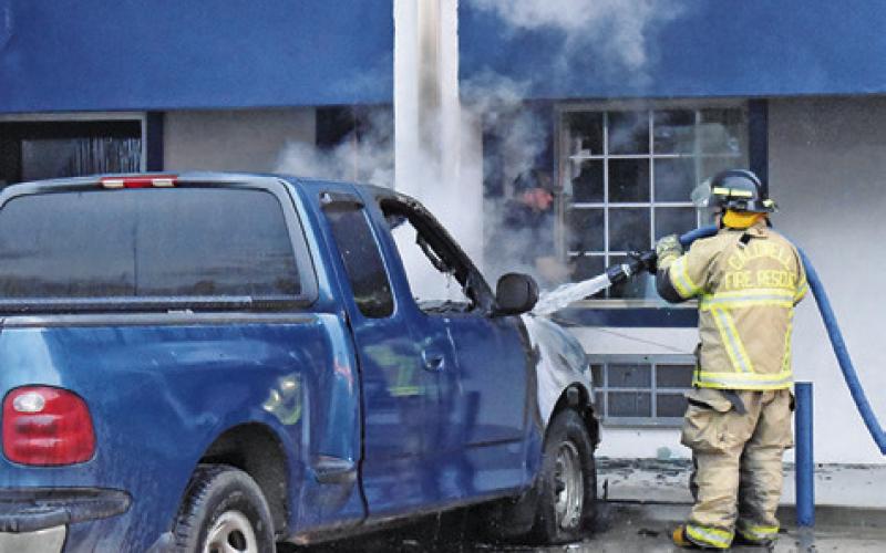 A FIREFIGHTER SPRAYS water on this truck at the scene.