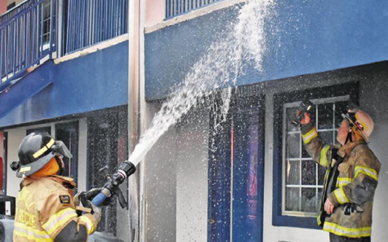 FIREFIGHTERS SPRAY WATER on the exterior of the walls.