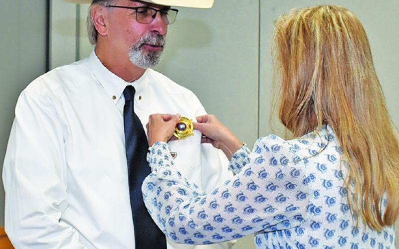 DAVID SIMMONS gets his badge as Burleson County chief deputy at the Monday, July 14, swearing in ceremony at the civic center.