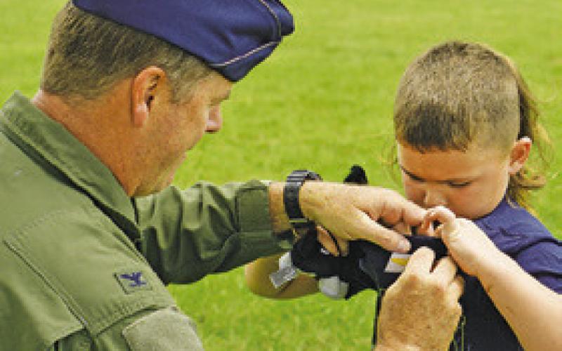 COLONEL LANCE Burnet, USAF (ret.), places wings on this child during last Thursday’s Harrie P. Woodson Library’s “Ready for Take-Off!” event featuring planes.