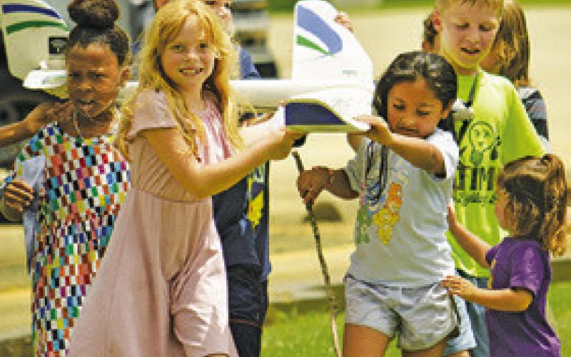 AREA CHILDREN RETURN this radiocontrolled plane to Elbert Oberts, its owner, during the Harrie P. Woodson Library’s “Ready for Take-Off!” event featuring planes.