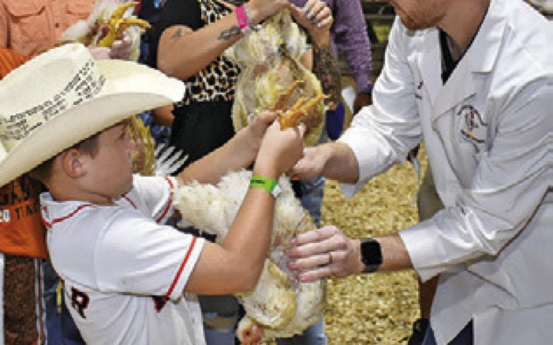 BRANSYN WILSON displays his broiler for Judge Jacob Price at the county fair.