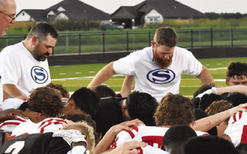 SNOOK AND BREMOND coaches and players pray together after the Friday scrimmage in Snook. -- Tribune photo by Roy Sanders