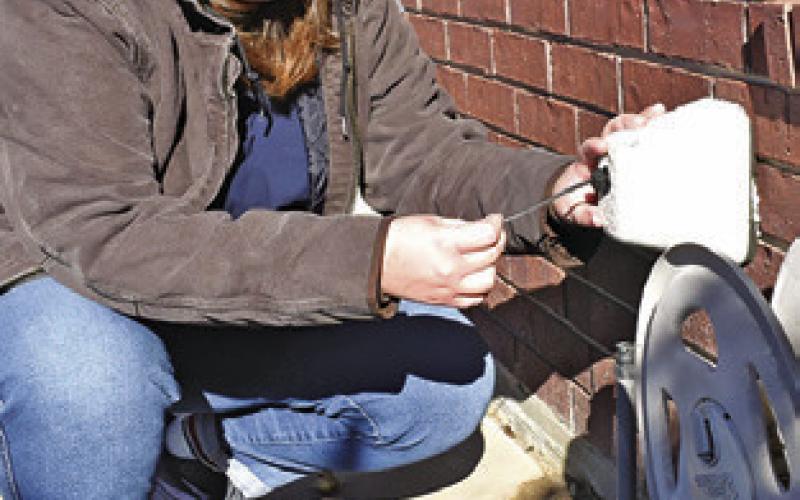 KIMBERLY HUTCHESON checks the covering of this outdoor water spigot as the recent Arctic blast arrived in Burleson County. Tribune photo by Roy Sanders