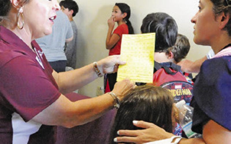 HOLLY NARRO WITH the county’s Texas A&amp;amp;M AgriLife Extension Office directs this parent during Monday’s “Back-to-School Blast” at the Burleson County Expo Center. Tribune photo by Denise Squier