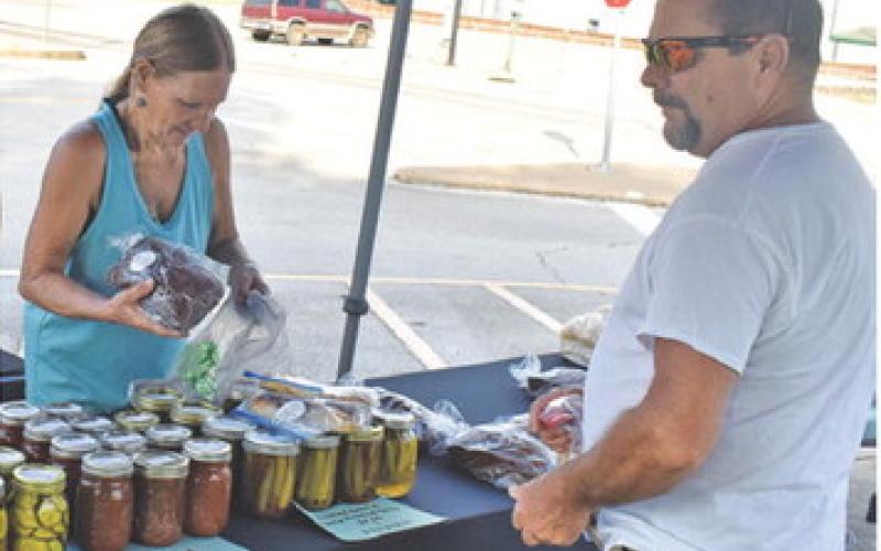 VICKIE DASH VISITS with a customer on Saturday at the weekly farmers market in downtown Caldwell. Local residents enjoy the market.